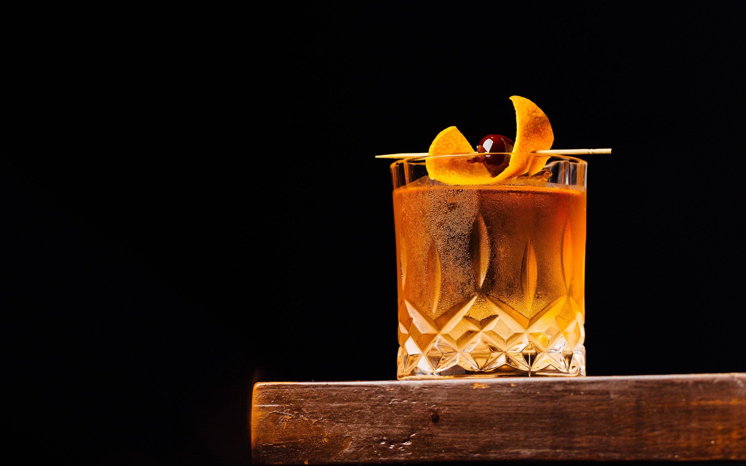 Cocktail in a glass with an orange twist on a dark background