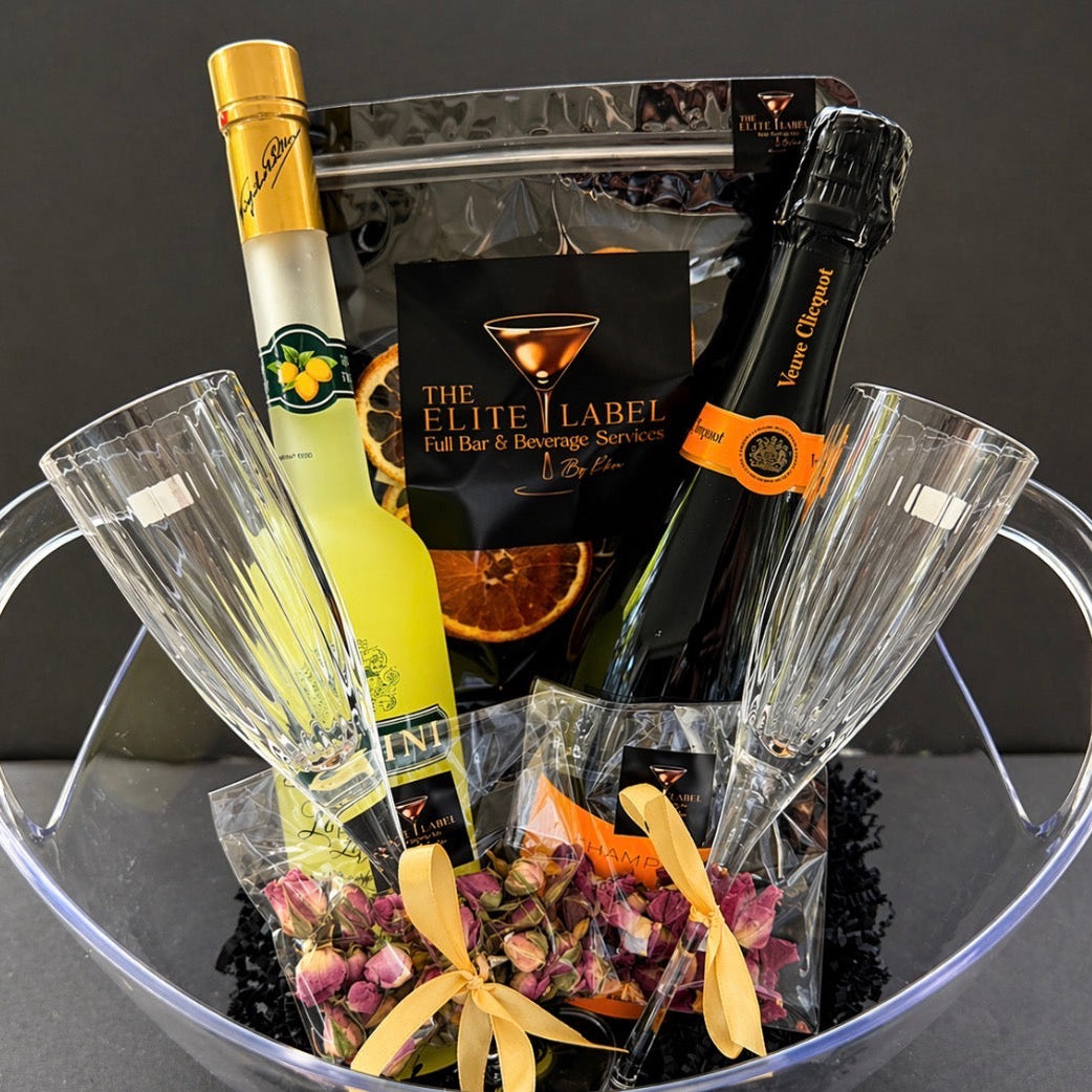The Elite Label branded cocktail Gift basket with champagne, liqueur, and glasses on a dark background