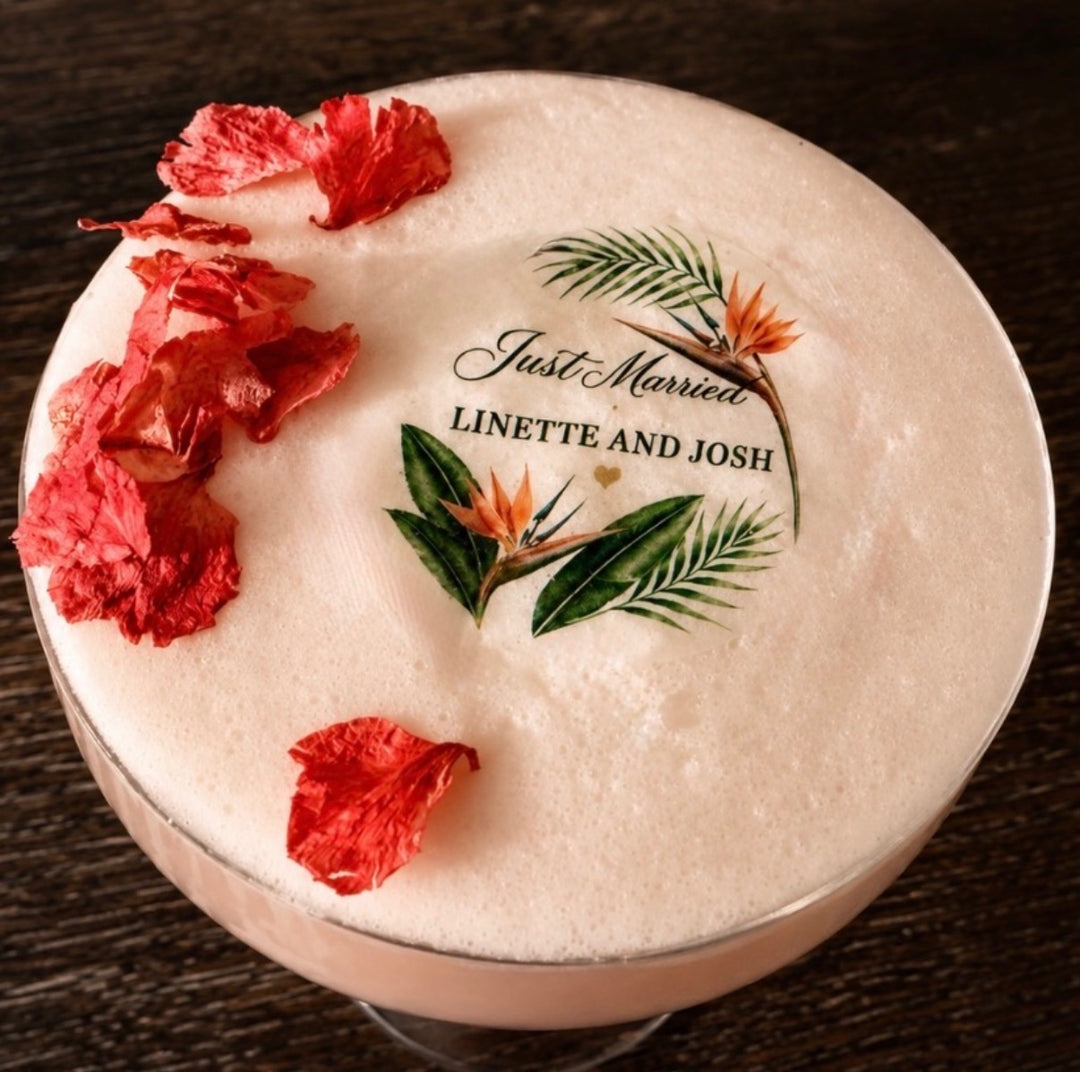 Cocktail with red flowers and 'Just Married' edible cocktail topper on a dark surface