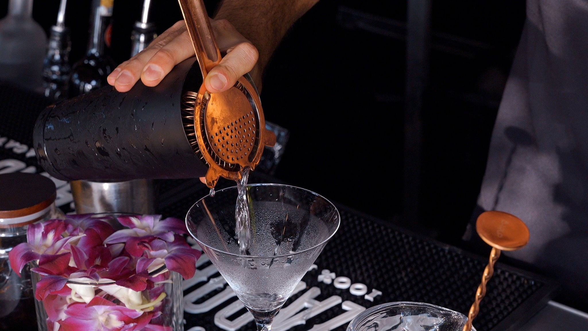 Barista pouring a drink into a martini glass with a focus on the action.