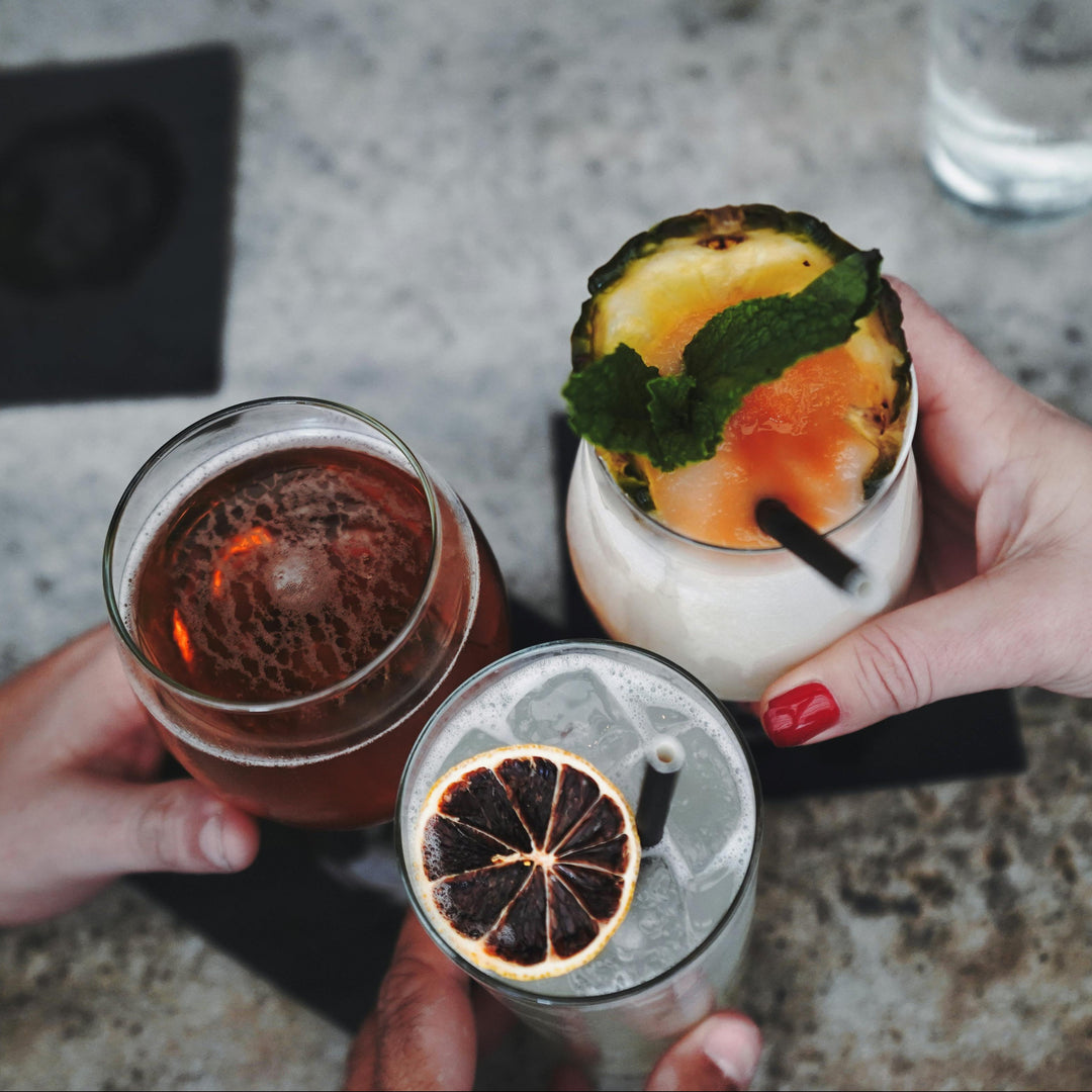 Three craft cocktails with dried fruit garnishes held together