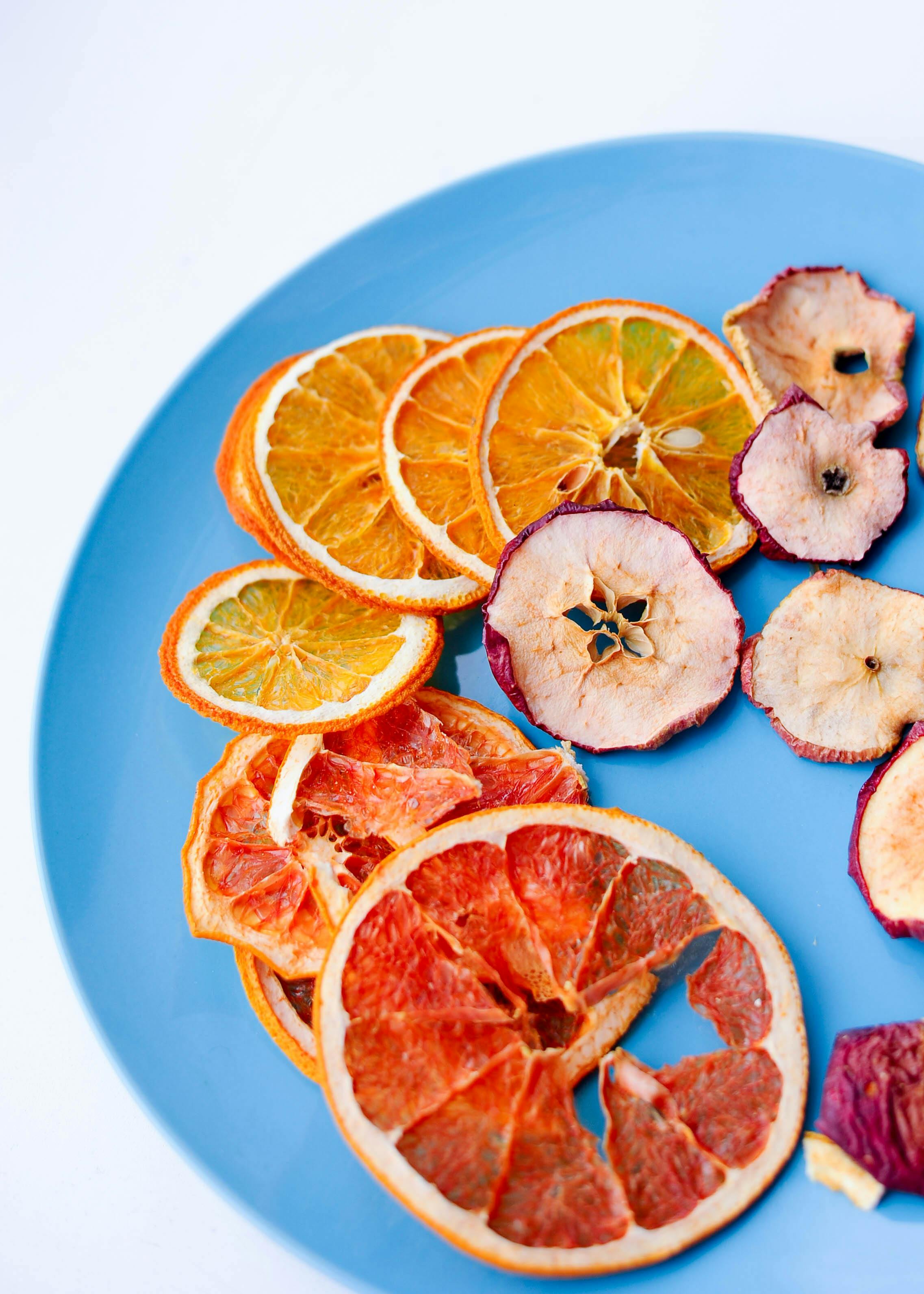Dried orange wheels and dehydrated apple slices on a blue plate