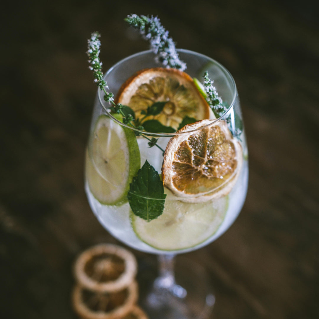 Craft Cocktail with lemon slices, lime wheel, and lavender on a dark background